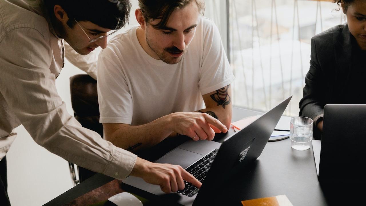 Two men looking and pointing at a laptop screen