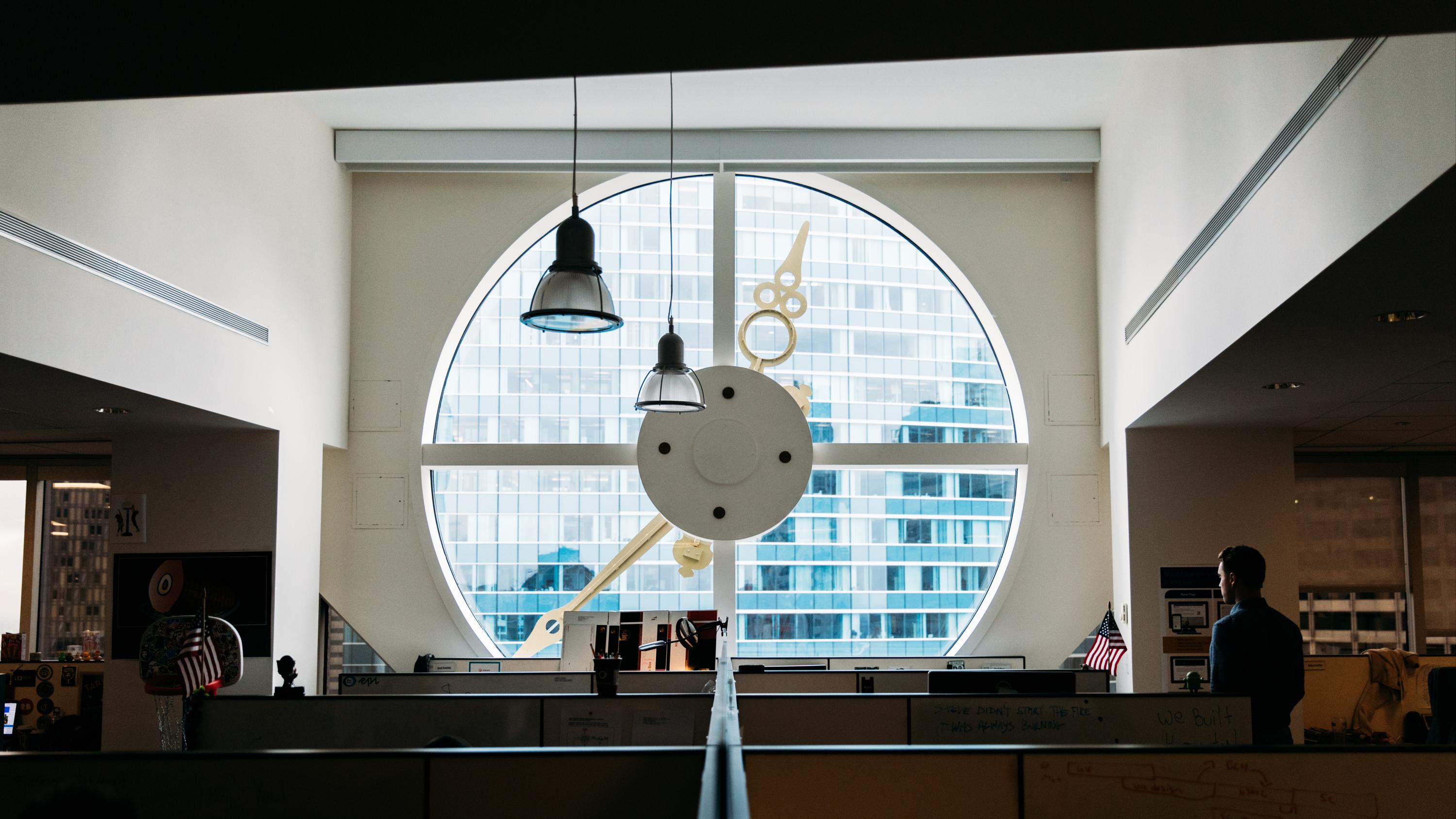 Inside of an office with cubicles and a large round window