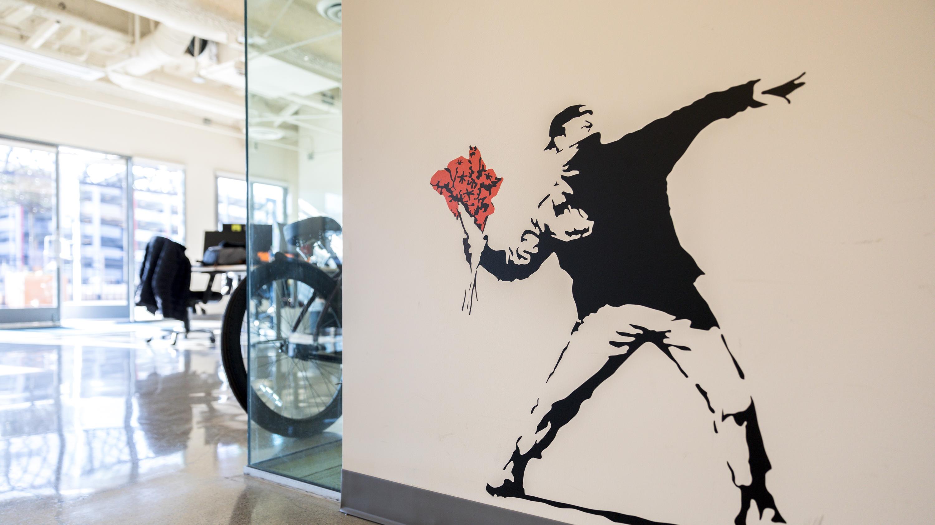Wall with a mural of a man preparing to throw a bouquet of roses